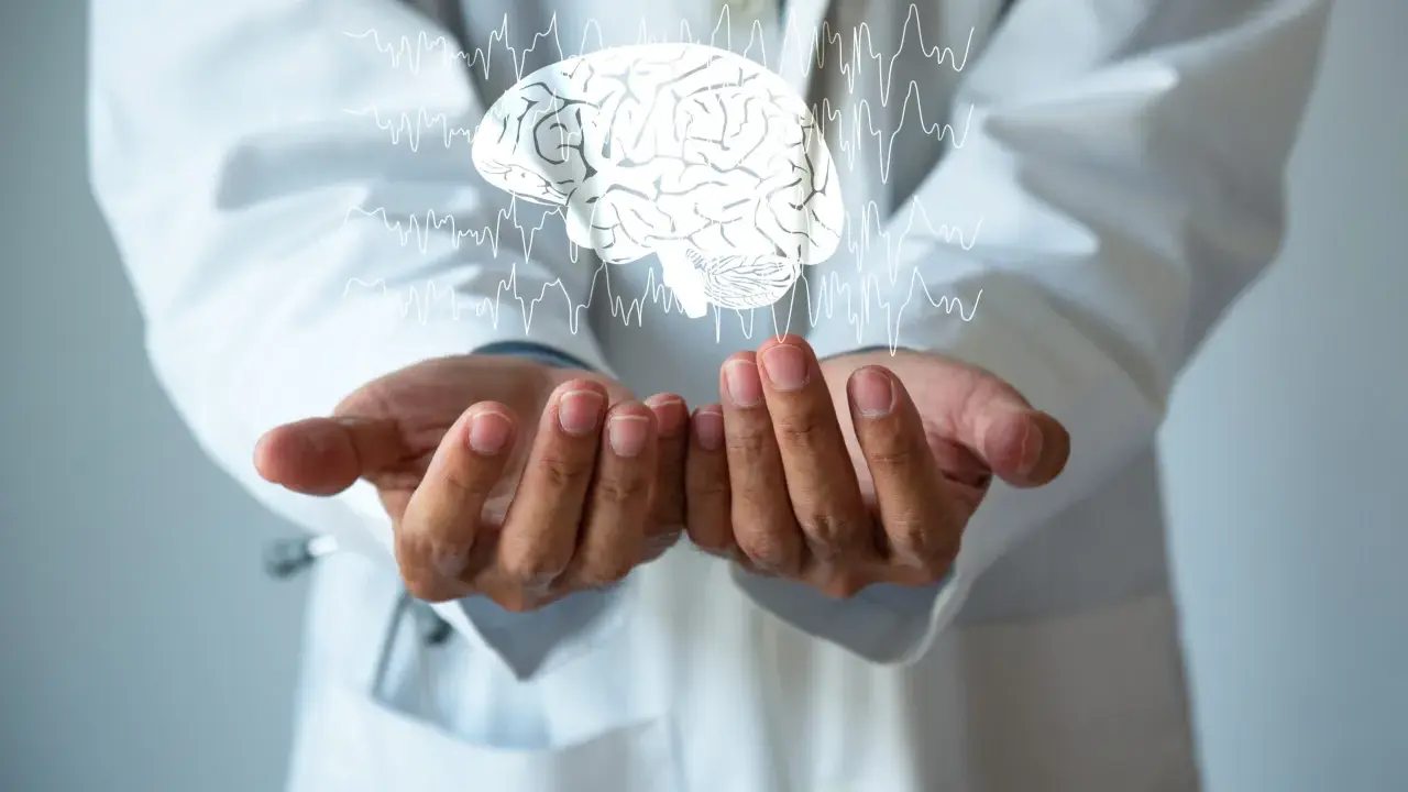 Dłonie lekarza w białym kitlu unoszą cyfrowy mózg z liniami EKG. Może to symbolizować diagnozę i leczenie chorób neurologicznych, np. i69 kod choroby.