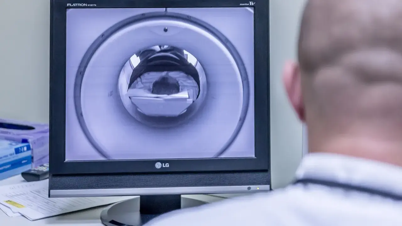 Opis rezonansu magnetycznego głowy. Na ekranie widać wnętrze aparatu MRI, przez które przechodzi pacjent.