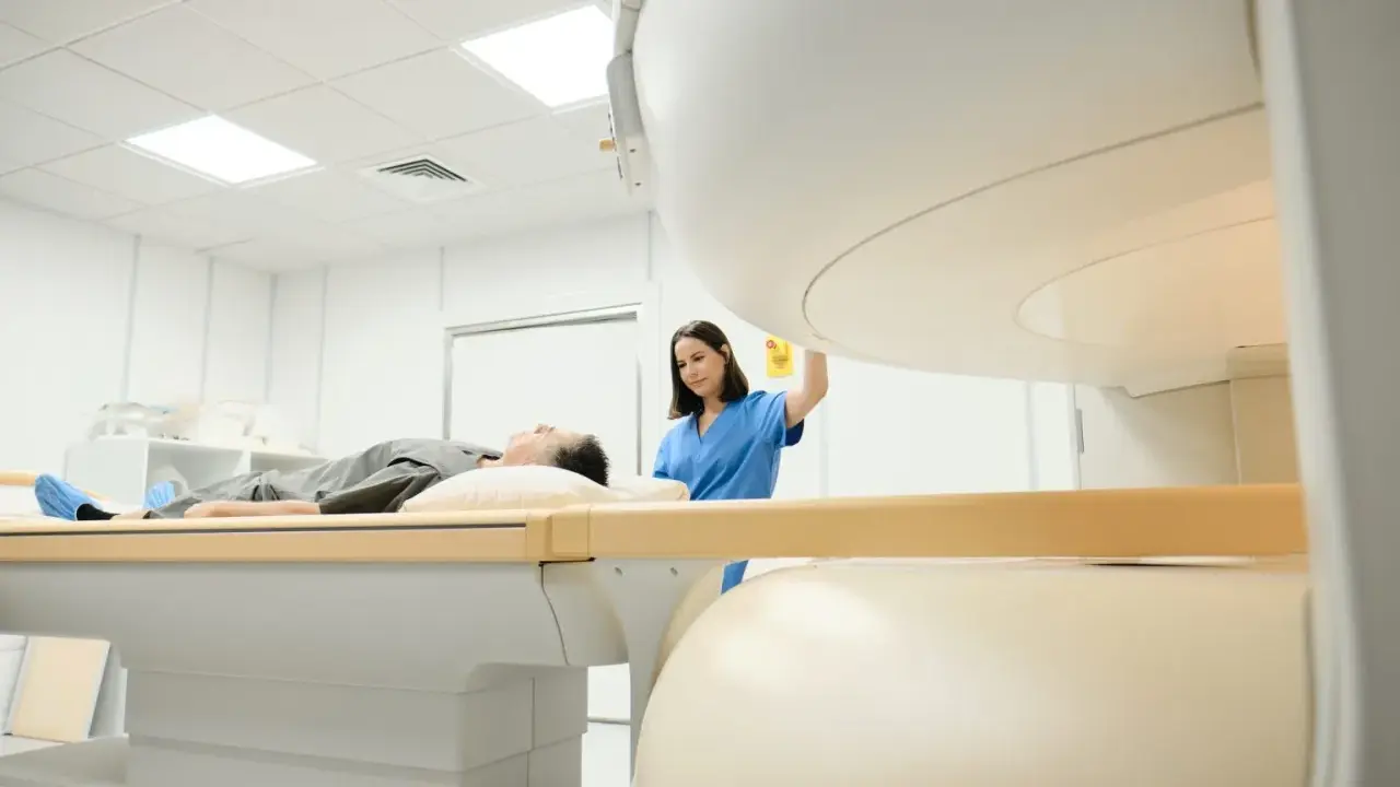 Pacjent leży na stole do rezonansu magnetycznego, pielęgniarka przygotowuje badanie. Rezonans barku interpretacja jest kluczowa dla diagnozy.