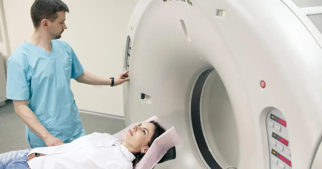 Pacjentka leży na stole do rezonansu, a technik przygotowuje aparat do badania. Rezonans całego organizmu co wykrywa? To zaawansowana diagnostyka obrazowa.