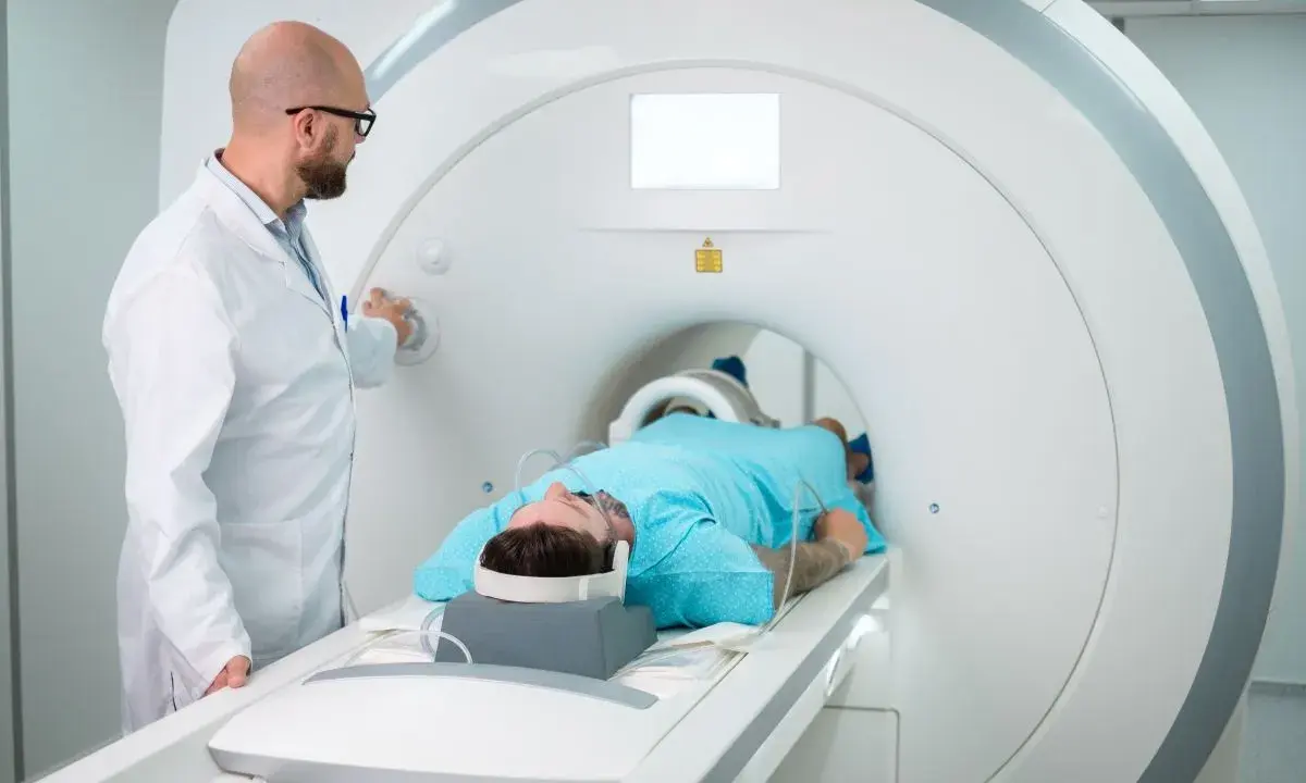 Lekarz nadzoruje badanie rezonansem kolana pacjenta leżącego w aparacie MRI.