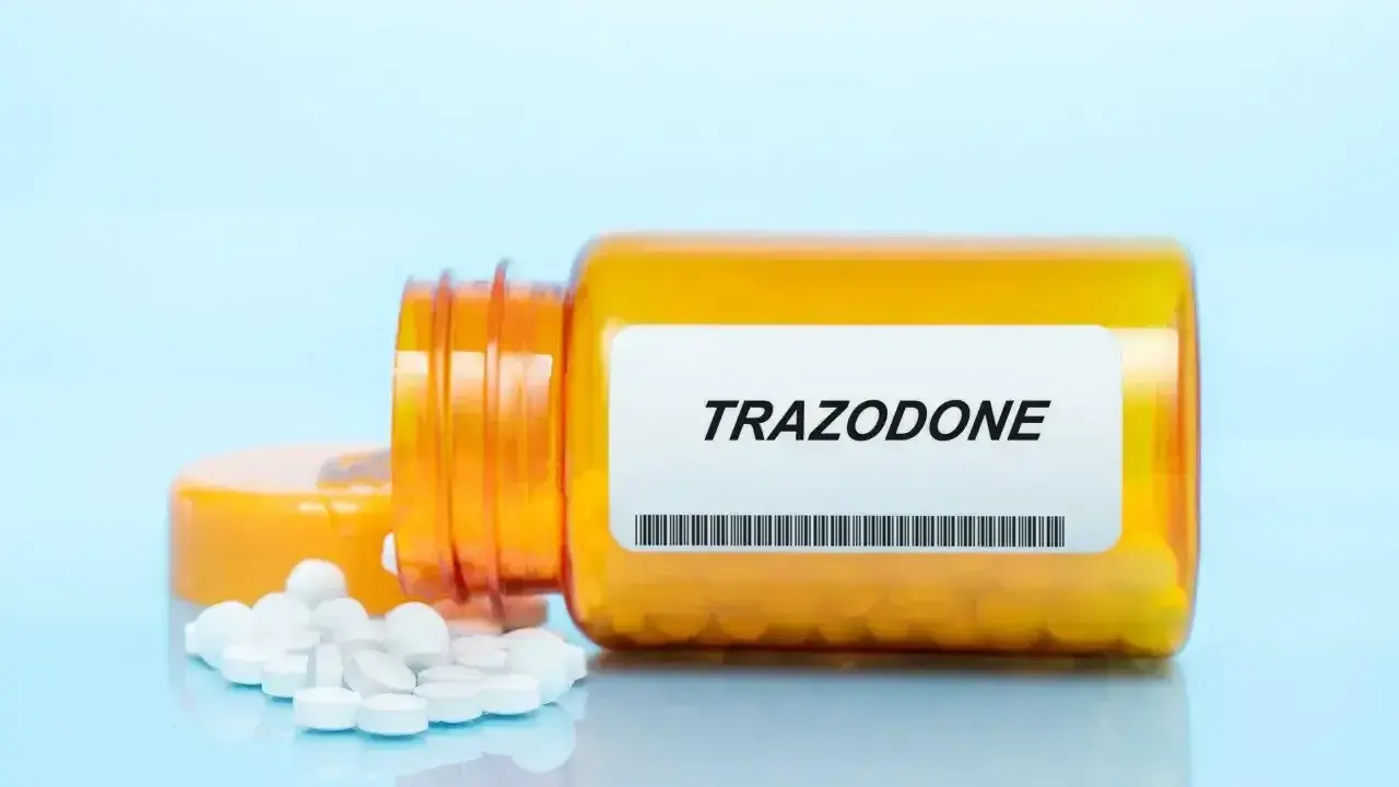 Pomarańczowa butelka z tabletkami trazodone neuraxpharm, kilka tabletek rozsypanych obok.