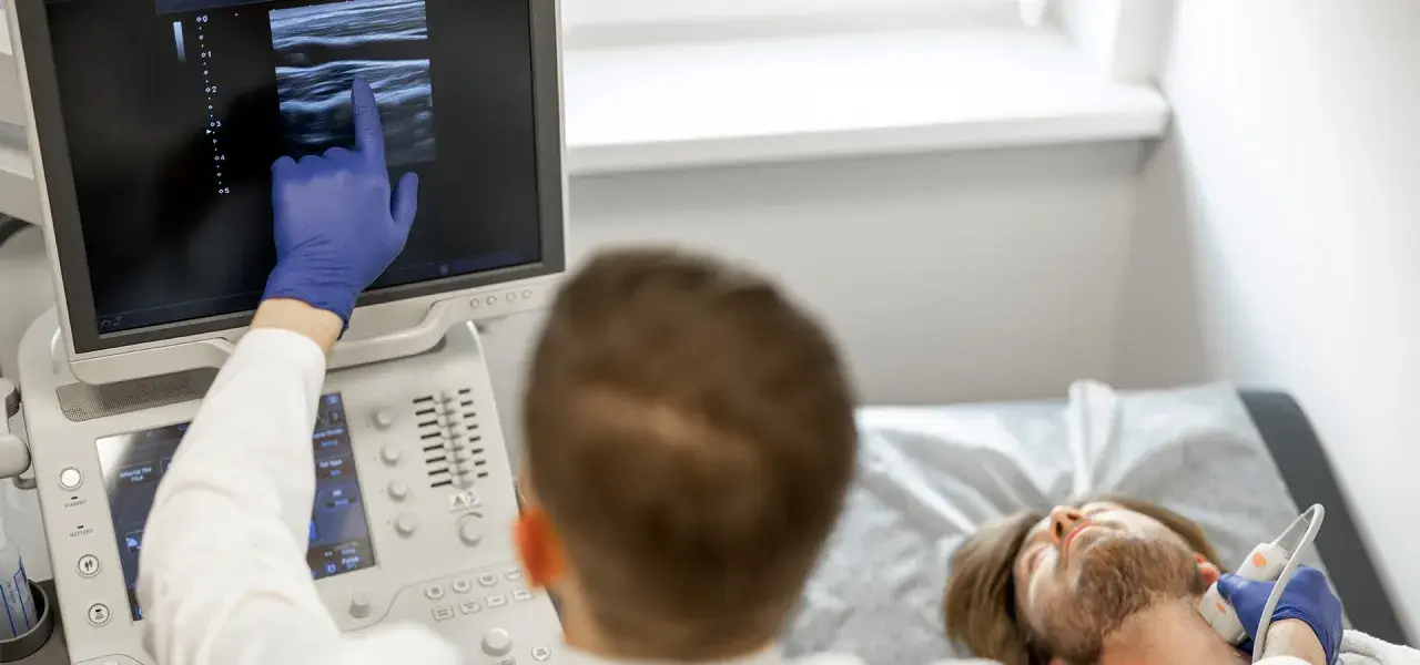 Lekarz wykonuje badanie doppler tętnic mózgowych, analizując obraz na monitorze USG.