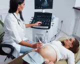 Lekarka wykonuje badanie USG ciężarnej. Na ekranie widać obraz, a lekarz steruje aparaturą.