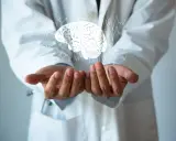 Dłonie lekarza w białym kitlu unoszą cyfrowy mózg z liniami EKG. Może to symbolizować diagnozę i leczenie chorób neurologicznych, np. i69 kod choroby.
