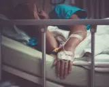 Pacjent w łóżku szpitalnym, z kroplówką, cierpiący. Może to być objaw wstrząsu septycznego, kod ICD-10 A41.