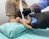 Lekarz wykonuje USG dłoni pacjenta z powodu bólu palca, szukając przyczyny zgodnej z ICD-10.