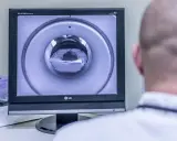 Opis rezonansu magnetycznego głowy. Na ekranie widać wnętrze aparatu MRI, przez które przechodzi pacjent.