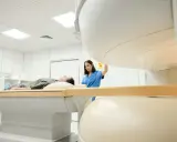 Pacjent leży na stole do rezonansu magnetycznego, pielęgniarka przygotowuje badanie. Rezonans barku interpretacja jest kluczowa dla diagnozy.
