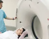 Pacjentka leży na stole do rezonansu, a technik przygotowuje aparat do badania. Rezonans całego organizmu co wykrywa? To zaawansowana diagnostyka obrazowa.