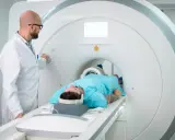 Lekarz nadzoruje badanie rezonansem kolana pacjenta leżącego w aparacie MRI.