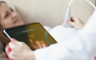 Kobieta na tablecie widzi obraz z USG. To badanie ultrasonograficzne, które pokazuje rozwój dziecka.