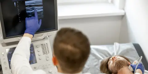 Lekarz wykonuje badanie doppler tętnic mózgowych, analizując obraz na monitorze USG.