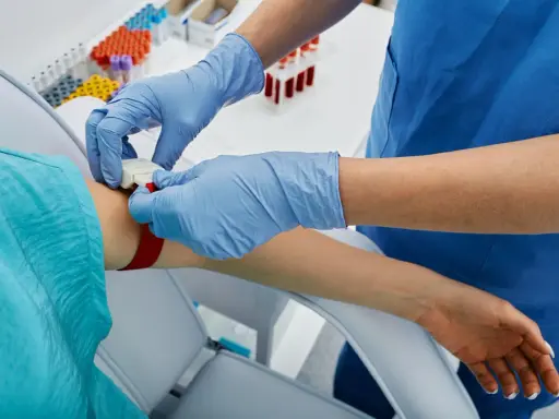 Pielęgniarka zakłada opaskę uciskową na rękę pacjenta, przygotowując się do pobrania krwi. To ważny krok, apo atorva na co.
