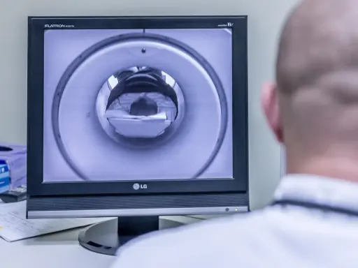 Opis rezonansu magnetycznego głowy. Na ekranie widać wnętrze aparatu MRI, przez które przechodzi pacjent.