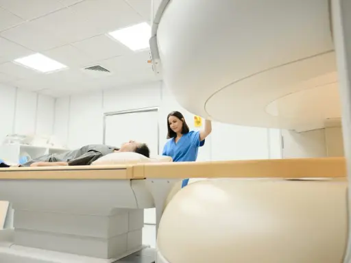 Pacjent leży na stole do rezonansu magnetycznego, pielęgniarka przygotowuje badanie. Rezonans barku interpretacja jest kluczowa dla diagnozy.