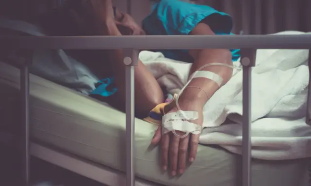 Pacjent w łóżku szpitalnym, z kroplówką, cierpiący. Może to być objaw wstrząsu septycznego, kod ICD-10 A41.