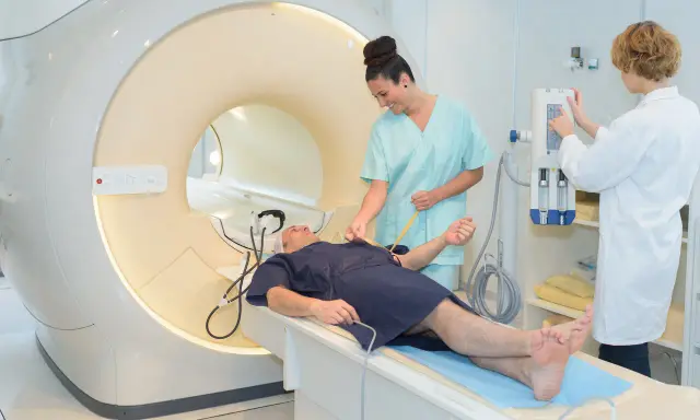 Pacjent na stole do rezonansu magnetycznego, przygotowywany przez pielęgniarki. Szybkie wyniki badań to klucz do diagnozy.