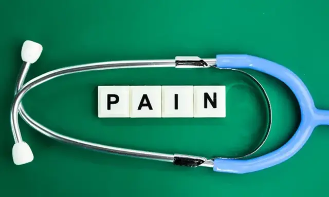 Stetoskop i kostki z literami "PAIN" symbolizują ból, który może być klasyfikowany według ICD-10.