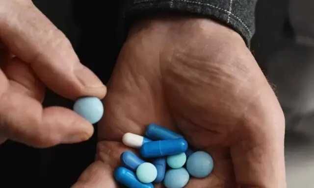 Dłoń trzyma garść niebieskich i białych tabletek. Czy Citaxin to psychotrop?