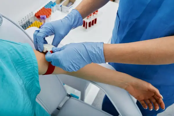 Pielęgniarka zakłada opaskę uciskową na rękę pacjenta, przygotowując się do pobrania krwi. To ważny krok, apo atorva na co.