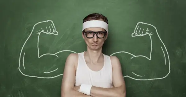 Chudy mężczyzna w okularach i opasce na głowie, z narysowanymi po bokach bicepsami, jakby po zażyciu omnadren 250.