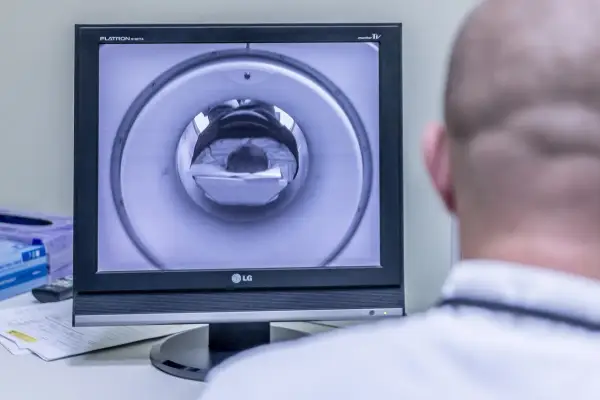 Opis rezonansu magnetycznego głowy. Na ekranie widać wnętrze aparatu MRI, przez które przechodzi pacjent.