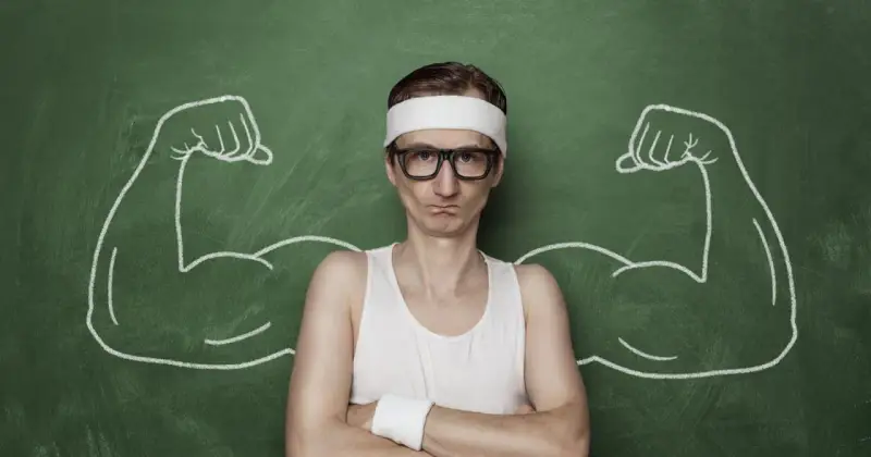 Chudy mężczyzna w okularach i opasce na głowie, z narysowanymi po bokach bicepsami, jakby po zażyciu omnadren 250.