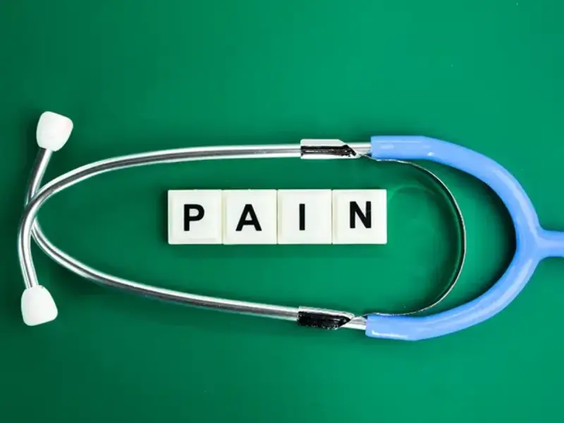 Stetoskop i kostki z literami "PAIN" symbolizują ból, który może być klasyfikowany według ICD-10.