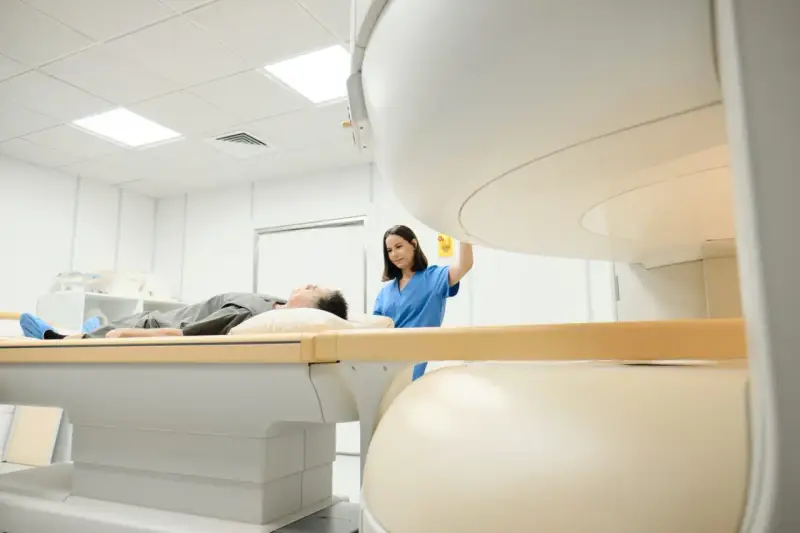 Pacjent leży na stole do rezonansu magnetycznego, pielęgniarka przygotowuje badanie. Rezonans barku interpretacja jest kluczowa dla diagnozy.